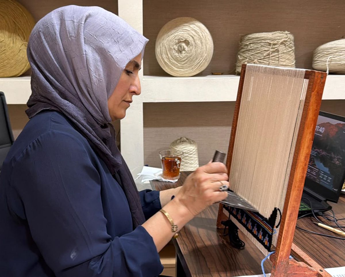 Hatice Mengi'nin minyatür tezgahta halı dokuma sanatı öğrettiği bir görsel.