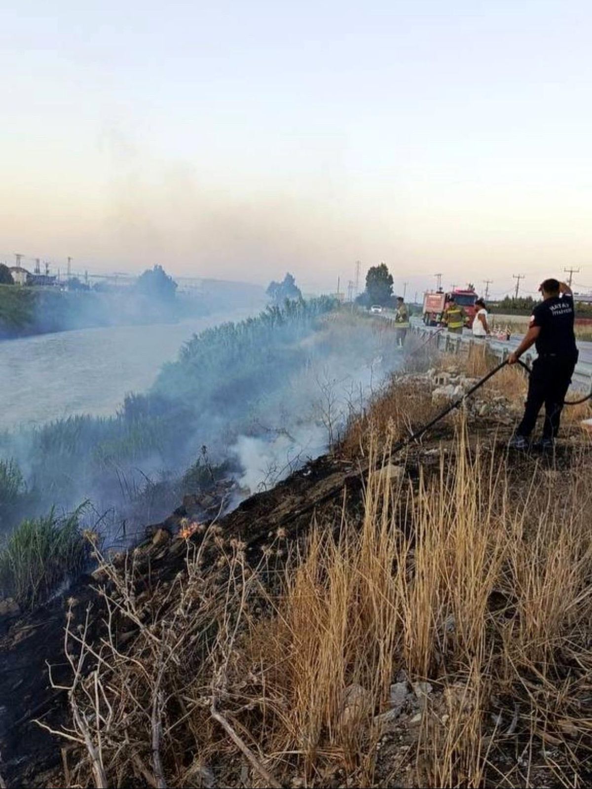 Hatay'ın Antakya ilçesinde Asi Nehri kenarındaki sazlık alanda çıkan yangına müdahale eden itfaiye ekipleri.