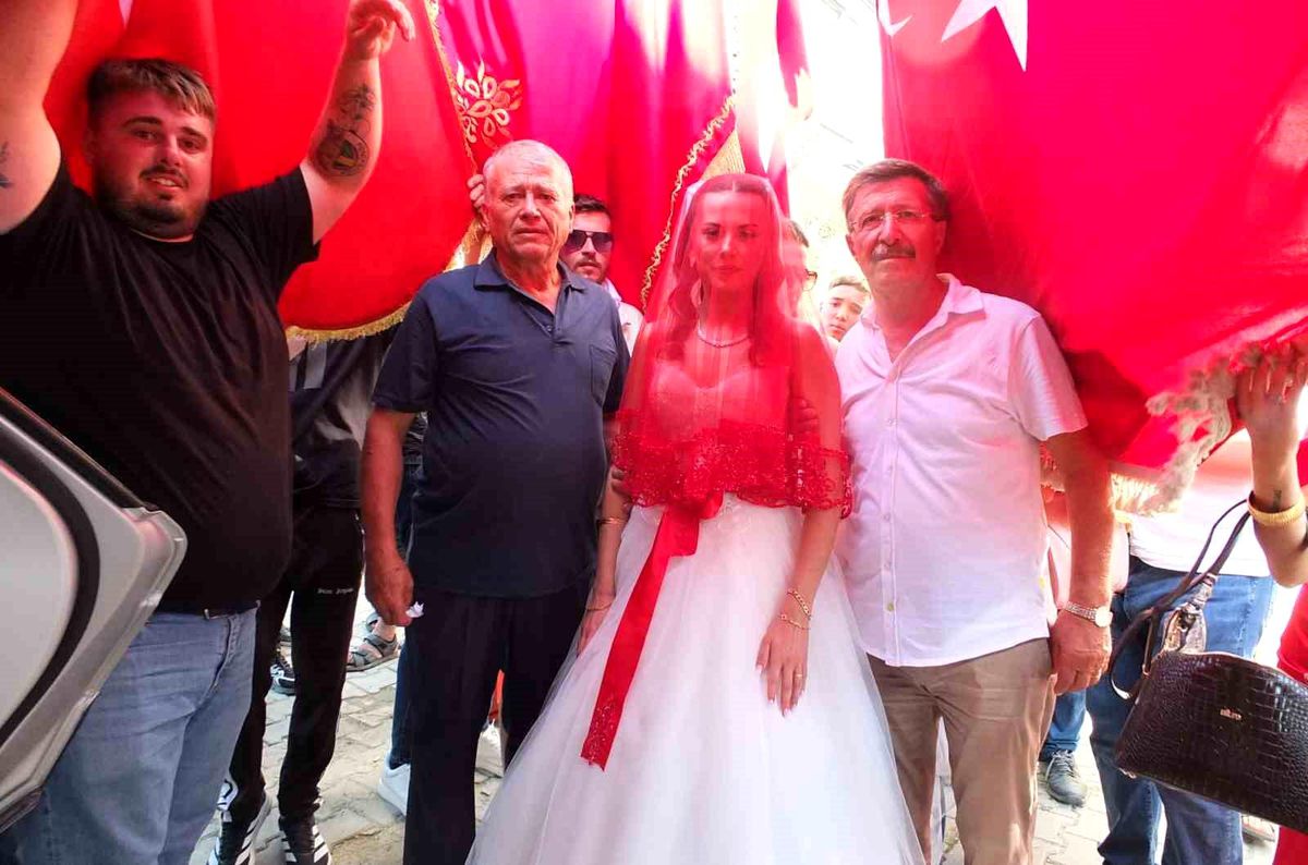 Balıkesir'in Burhaniye ilçesinde Türk bayrakları eşliğinde gelin arabasına binen bir gelin.