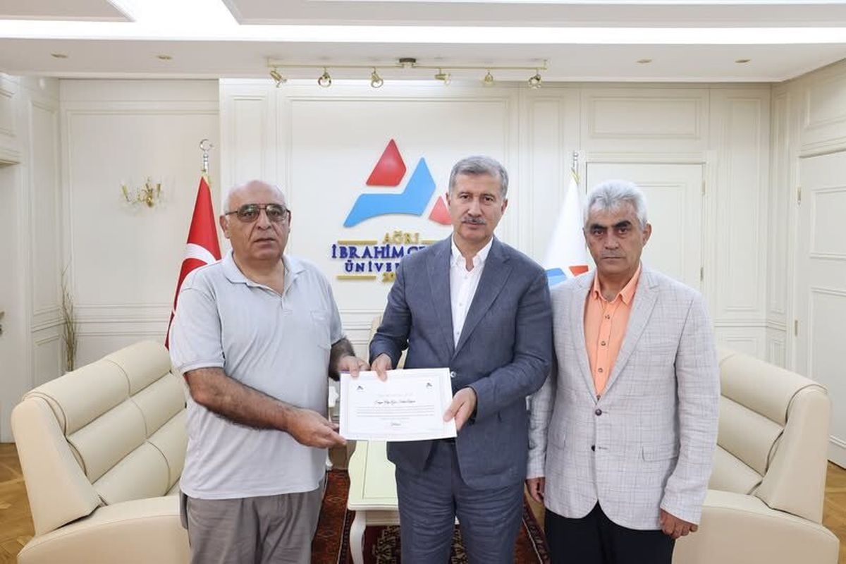 AİCÜ Rektörü Prof. Dr. İlhami Gülçin'in, emekli Öğretim Görevlisi Salim Arpacı'ya teşekkür belgesi takdim ettiği an.