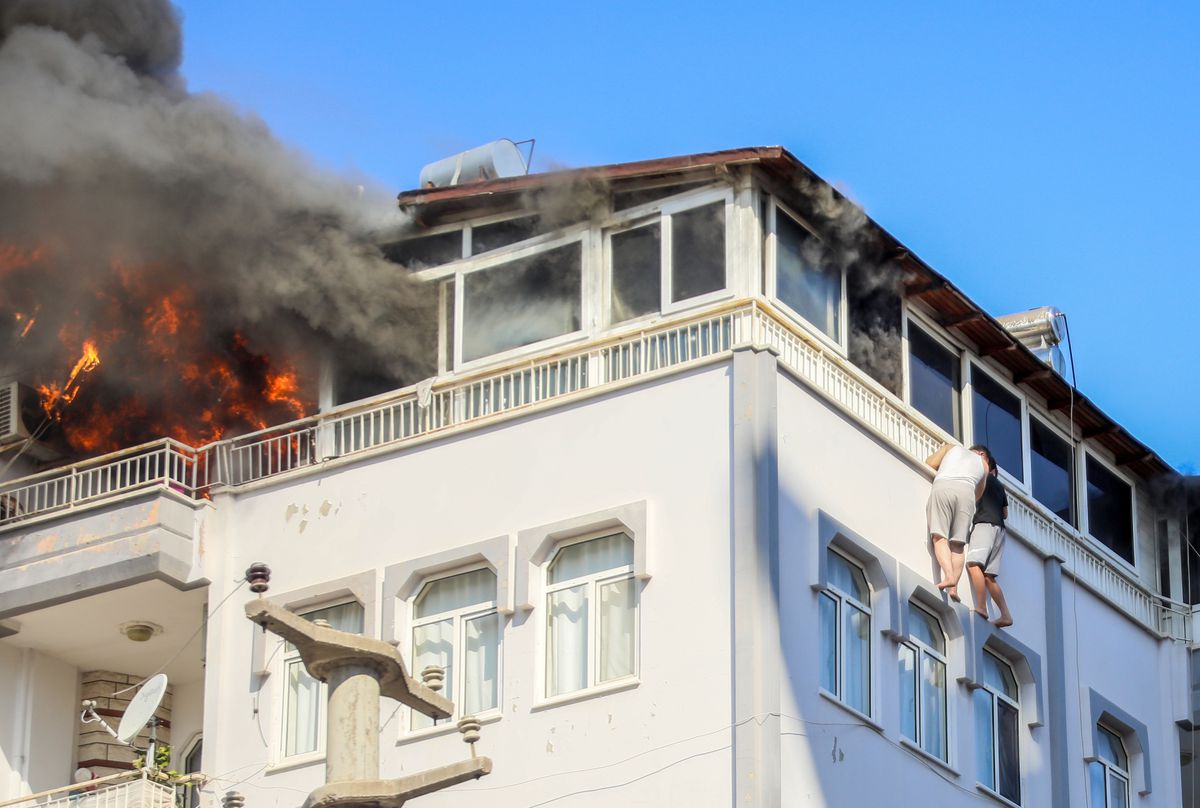 Antalya'da bir apartman dairesinde çıkan yangında mahsur kalan iki kişi, pencereden korkuluk demirlerine tutunarak itfaiye tarafından kurtarılıyor.