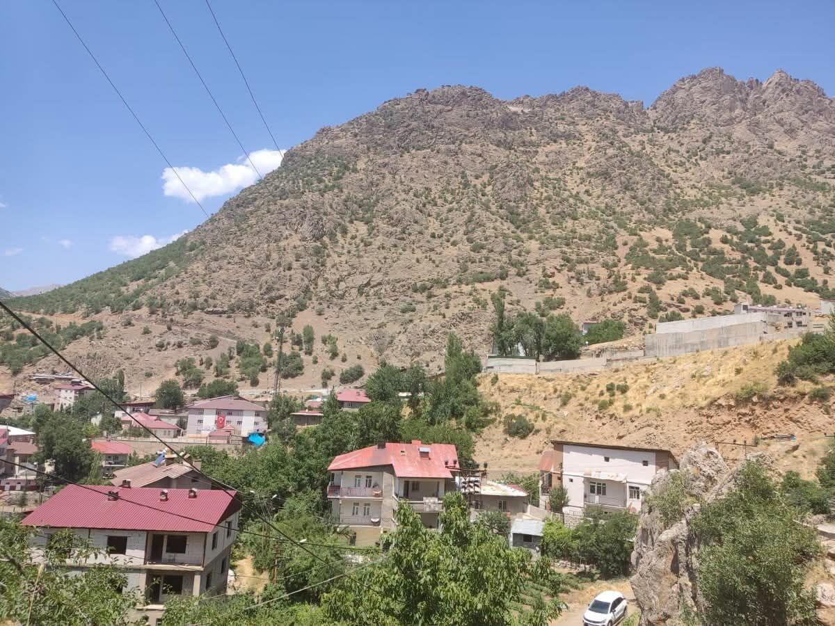 Askeri bir helikopterin iniş yaparken veya havalanırken çekilmiş bir görüntüsü, arka planda dağlık arazi görünüyor.