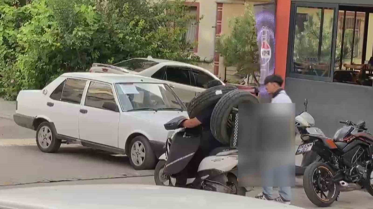 Ankara'da görenleri şaşkına çeviren kurye! Otomobil lastiğini boynuna asıp motosiklet kullandı