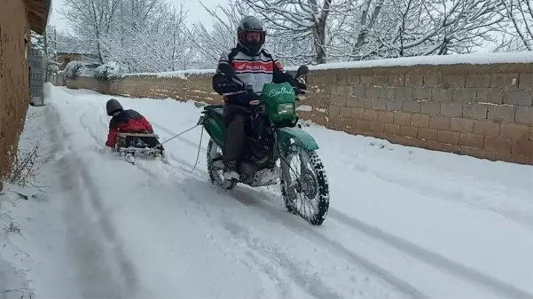 Motosiklete bağladığı kızaklarla çocukları karda eğlendirdi